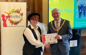 a photo of SUSU member receiving an award from the chair of Devon County Council